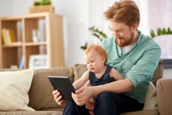 family, fatherhood and technology concept - happy red haired father and little baby daughter with tablet pc computer at home. father and baby daughter with tablet pc at home. father and baby daughter with tablet pc at home