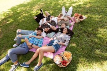 friendship, leisure and summer concept - group of happy friends chilling on picnic blanket at park. happy friends chilling on picnic blanket at summer. happy friends chilling on picnic blanket at summer