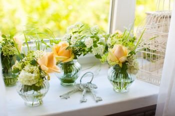 Small bouquets of beautiful roses and bunch of old keys on the windowsill.. White decoration of the room