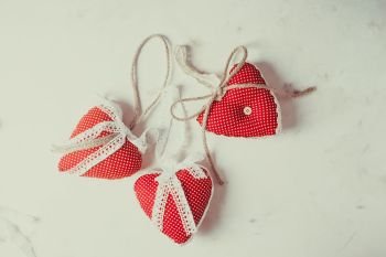 Red polka dot textile hearts hon the table. Process of sewing and design. Red polka dot textile hearts