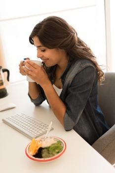 Young woman having breakfast on the computer desk