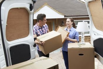 Young Couple Moving In To New Home  Unloading Removal Van