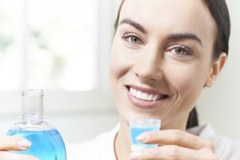 Portrait Of Woman With Beautiful Teeth Using Mouthwash In Bathroom