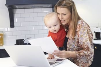 Busy Mother With Baby Coping With Stressful Day At Home