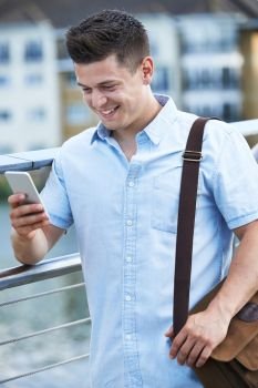 Young Man Texting On Mobile Phone Walking To Work