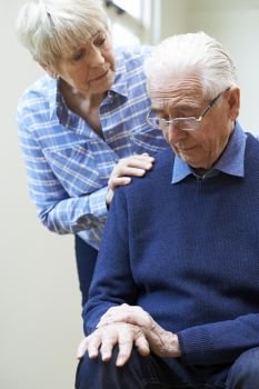 Senior Woman Comforts Husband Suffering With Parkinsons Diesease