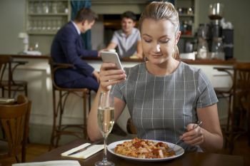 Female Food Blogger Posting Online Review Of Restaurant Meal Using Mobile Phone