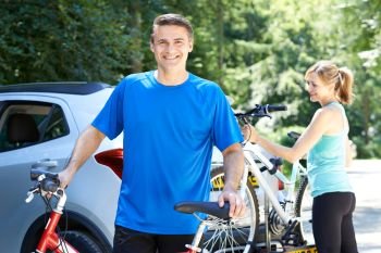 Mature Couple Taking Mountain Bikes From Rack On Car