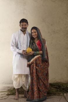 Portrait of Indian rural couple holding clay piggy bank