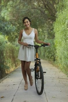 Smiling young woman in park with bicycle