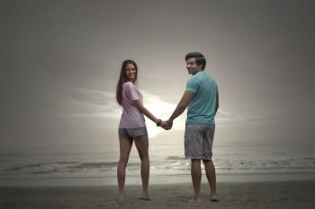Happy couple hand in hand on the beach