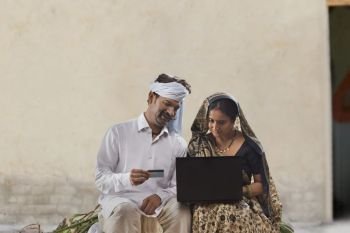 Rural couple using laptop and credit card doing online banking