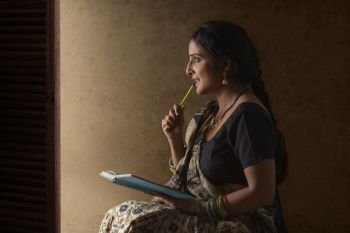Indian rural woman thinking while holding book and pencil