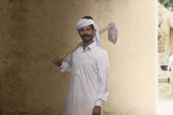 Portrait of Indian farmer carrying hoe on his shoulder