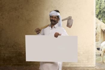 Indian farmer carrying hoe on his shoulder and holding placard
