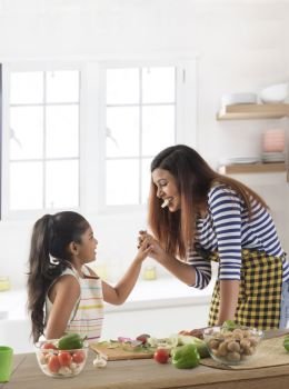 Mother and daughter eating cucumber in kitchen