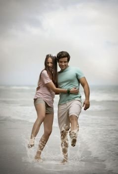 Playful young couple splashing in sea