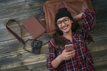Female tourist holding phone lying on wooden background