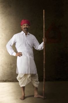 Portrait of farmer in traditional clothing holding stick