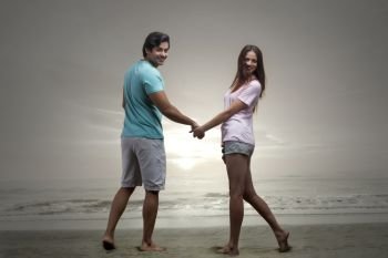 Happy couple hand in hand on the beach