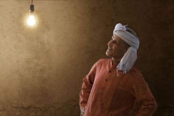 Senior rural man looking at light bulb in his house
