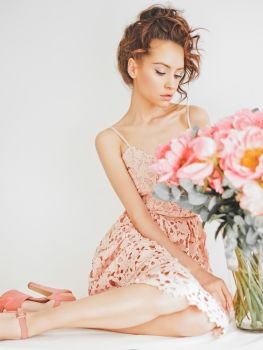 Home stylish fashion photo of beautiful young woman in lace dress with big bouquet of peony. Holidays and Events. Valentine’s Day. Spring blossom. Summer season.