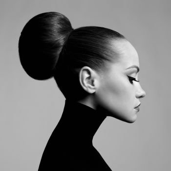 Black and white fashion art studio portrait of beautiful elegant woman in black turtleneck.  Hair is collected in high beam.  Elegant ballet style