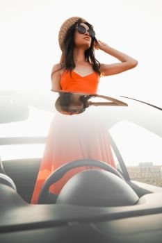 Outdoor lifestyle photo of beautiful happy woman in car cabriolet. Holiday and travel. Summer trip. Freedom, youth and carefree