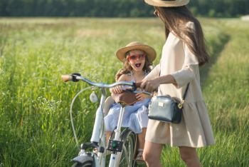Mother and daughter have bike ride on nature. Summertime activity