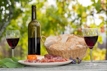 Country life setting with wine, fruits, cheese and meat. Outdoor