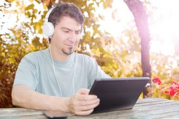 casual man working with a tablet pc, with headphones, outdoor