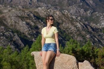 Young happy woman sitting on the rock mountain, relaxing and enjoying the valley view at Geres, Portuguese National Park. girl enjoying