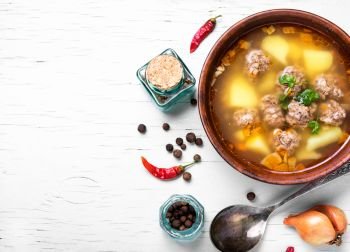 soup with meat balls. Meat soup in clay dish on a light wooden background
