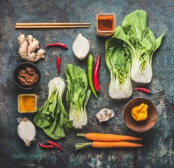 Flat lay with asian cooking ingredients : pak choi , ginger, spices, chili and chopsticks on dark rustic background, top view. Asian food and eating  concept: Chinese or Thai cuisine