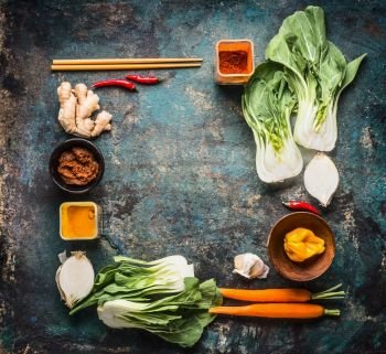 Asian cooking ingredients and spices with chopsticks on rustic background , top view , place for text, frame. Asian food and eating  concept: Chinese or Thai cuisine, flat lay