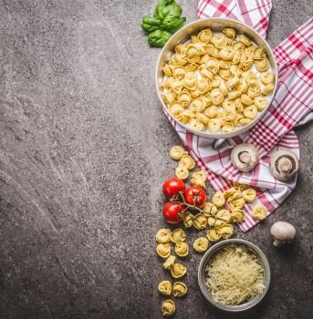 Raw tortellini pasta in bowl with ingredients, ready for cooking on rustic background , top view . Italian cuisine food concept