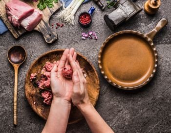 Female hands making meat balls on kitchen table background with  meat, force meat , meat grinder and spoon, top view. Cooking,recipes and eating concept