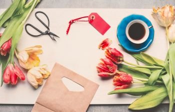 Creative layout  with spring tulips, cup of coffee, scissors, tag and shopping bag, top view