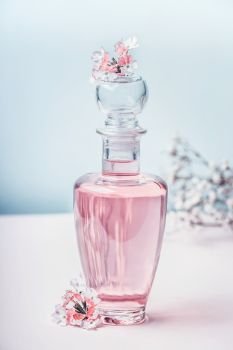 Floral Perfume bottle with flowers, front view. Perfumery, cosmetics, botanical fragrance concept. Pastel color. Beauty concept