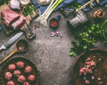 Meat balls meal cooking preparation with cooking spoon, kitchen tools and seasoning on rustic table background, top view, frame.