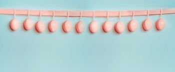 Easter banner or template. Beautiful pastel pink eggs hanging on ribbon at at blue turquoise background. Front view, copy space for greeting or invitation