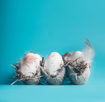 Eggs in carton box on blue background, front view. Easter layout concept