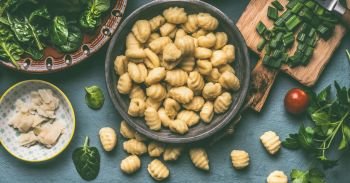 Potato gnocchi with vegetarian cooking ingredients: spinach and vegetables  on rustic table , top view