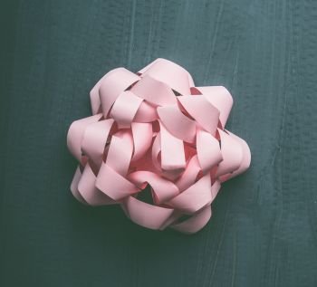 Pastel pink bow on gray background, creative holiday layout, top view