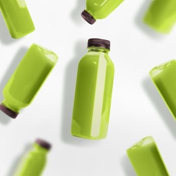 Green smoothie or juice bottles pattern on white background, top view, flat lay. Branding copy space