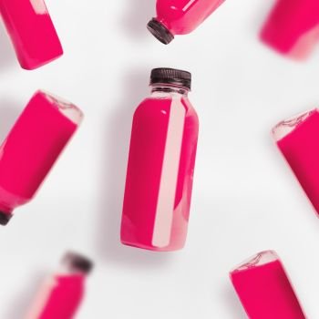 Pink smoothie or juice bottles pattern on white background, top view, flat lay. Branding copy space
