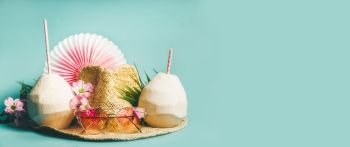 Beach accessories : straw hat, palm leaves, pink sun glasses, flowers and coconut cocktail on blue turquoise background, top view. Summer holiday and tropical vacation travel concept, banner