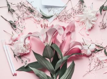 Florist work space with pastel pink lilies flowers, top view