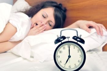 Woman yawns as the alarm is about to go off\
