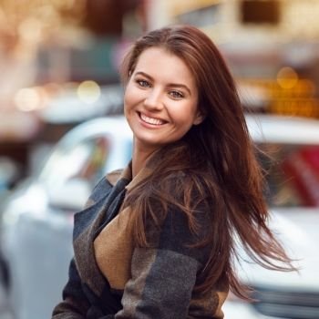 Close-up portrait of beautiful young adult woman with natural teeth smile looking at camera. Elegant brunette woman with hairstyle.